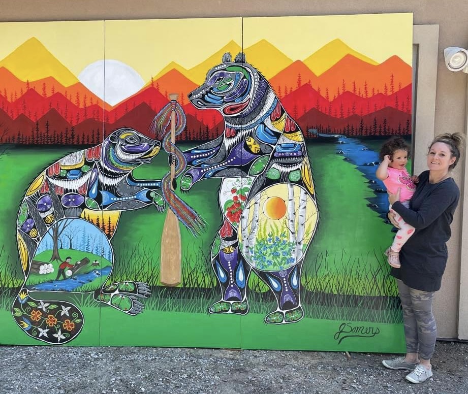 Community members engaging with a completed Woodland style mural, demonstrating the positive social and cultural impact of public art in a shared space.